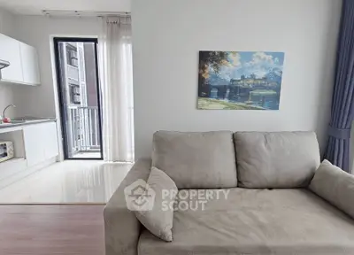 Modern living room with cozy sofa and open kitchen layout, featuring a balcony view.