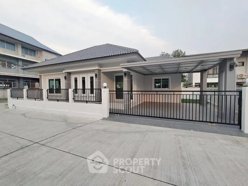 Modern single-story house with gated driveway and contemporary design.