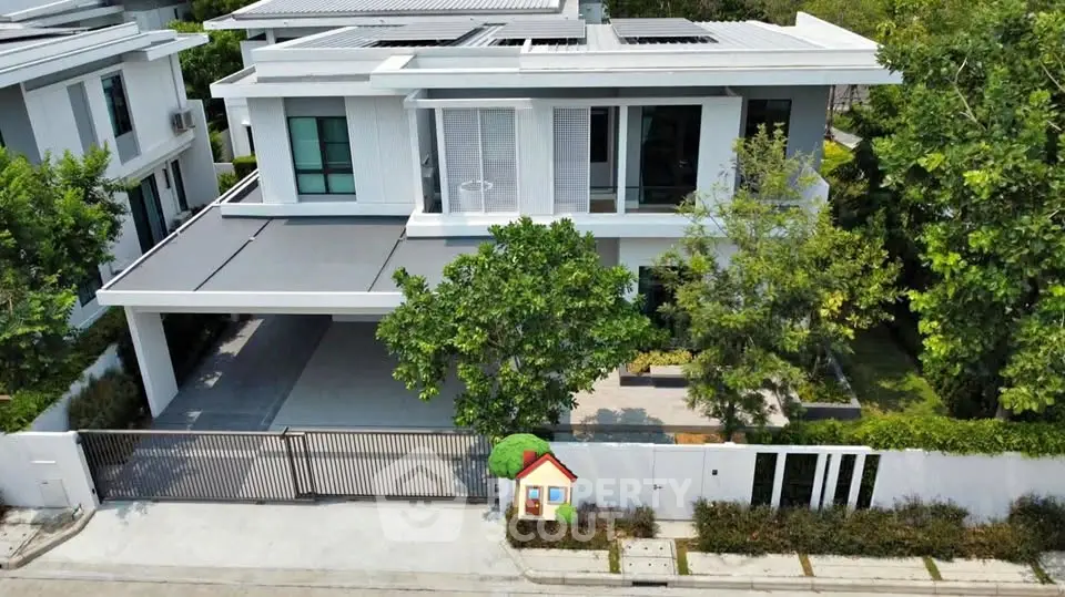 Modern two-story house with sleek design and spacious driveway in lush green setting.