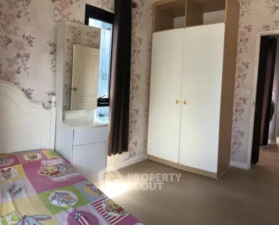 Charming bedroom with floral wallpaper and cozy furnishings, perfect for a peaceful retreat.