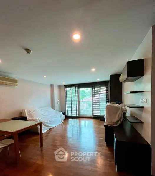Spacious living room with wooden flooring and large windows for natural light.