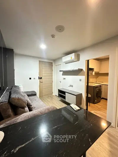 Modern living room with sleek furniture and open kitchen layout in a stylish apartment.