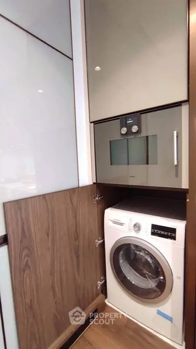 Modern kitchen with built-in appliances including washing machine and oven in sleek cabinetry.