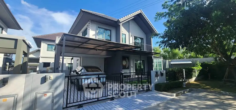 Modern two-story house with carport and lush garden in a serene neighborhood.