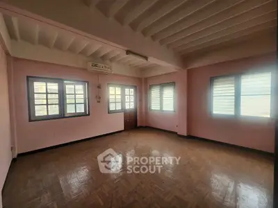 Spacious empty room with parquet flooring and large windows for natural light.
