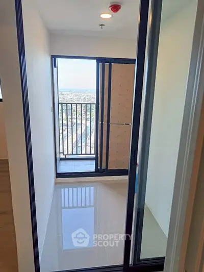 Bright balcony with sliding glass doors offering panoramic city views in modern apartment.