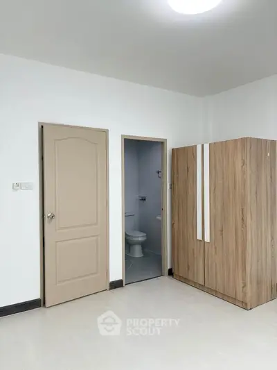 Minimalist bedroom with wooden wardrobe and bathroom access