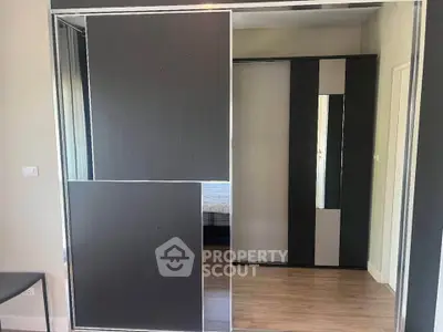 Modern bedroom with sleek sliding wardrobe doors and wooden flooring.