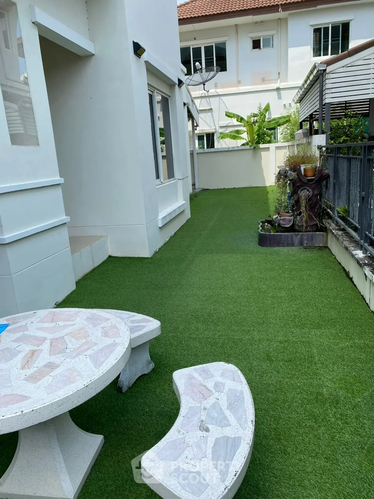 Charming outdoor garden area with artificial grass and stone seating, perfect for relaxation and entertaining.