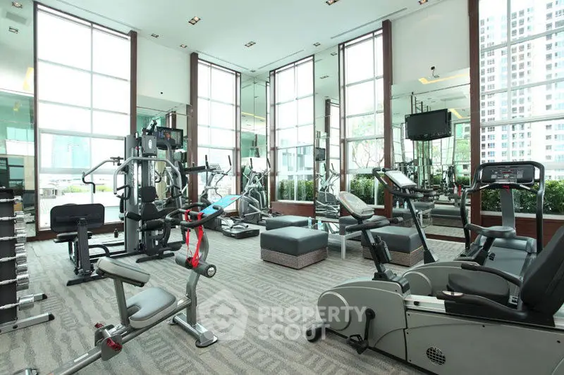 Luxurious modern gym with state-of-the-art equipment and floor-to-ceiling windows in a high-rise building.