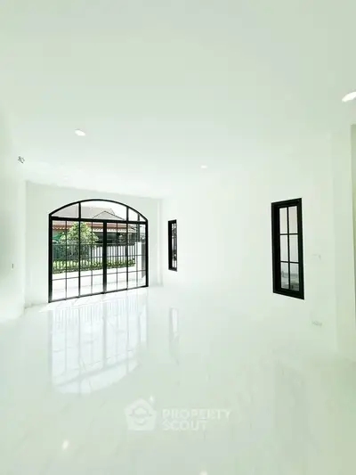 Spacious bright living room with large windows and glossy white flooring, perfect for modern living.