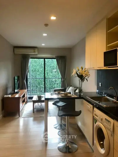 Modern open-plan living room with kitchen, featuring stylish decor and natural light.