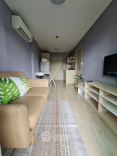 Modern living room with beige sofa, air conditioning, and open kitchen layout.