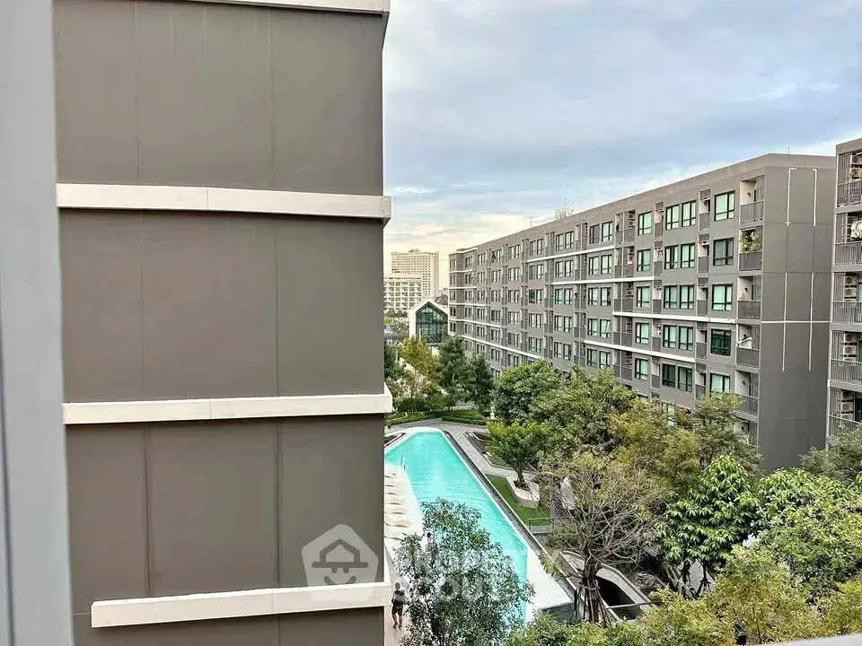 Modern apartment complex with pool view and lush greenery, offering urban living with serene surroundings.