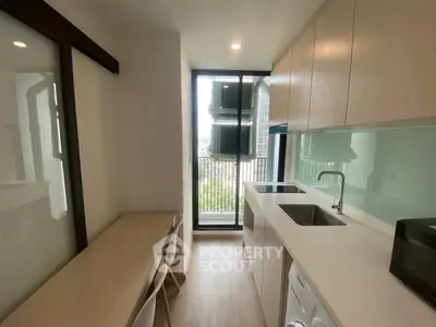 Modern kitchen with sleek cabinetry and balcony view, featuring built-in appliances and natural light.