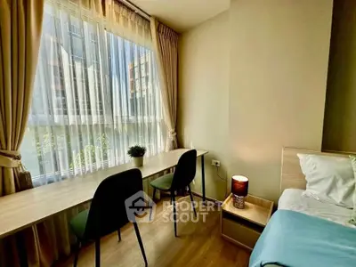 Bright bedroom with large window, modern desk, and cozy decor in urban apartment.