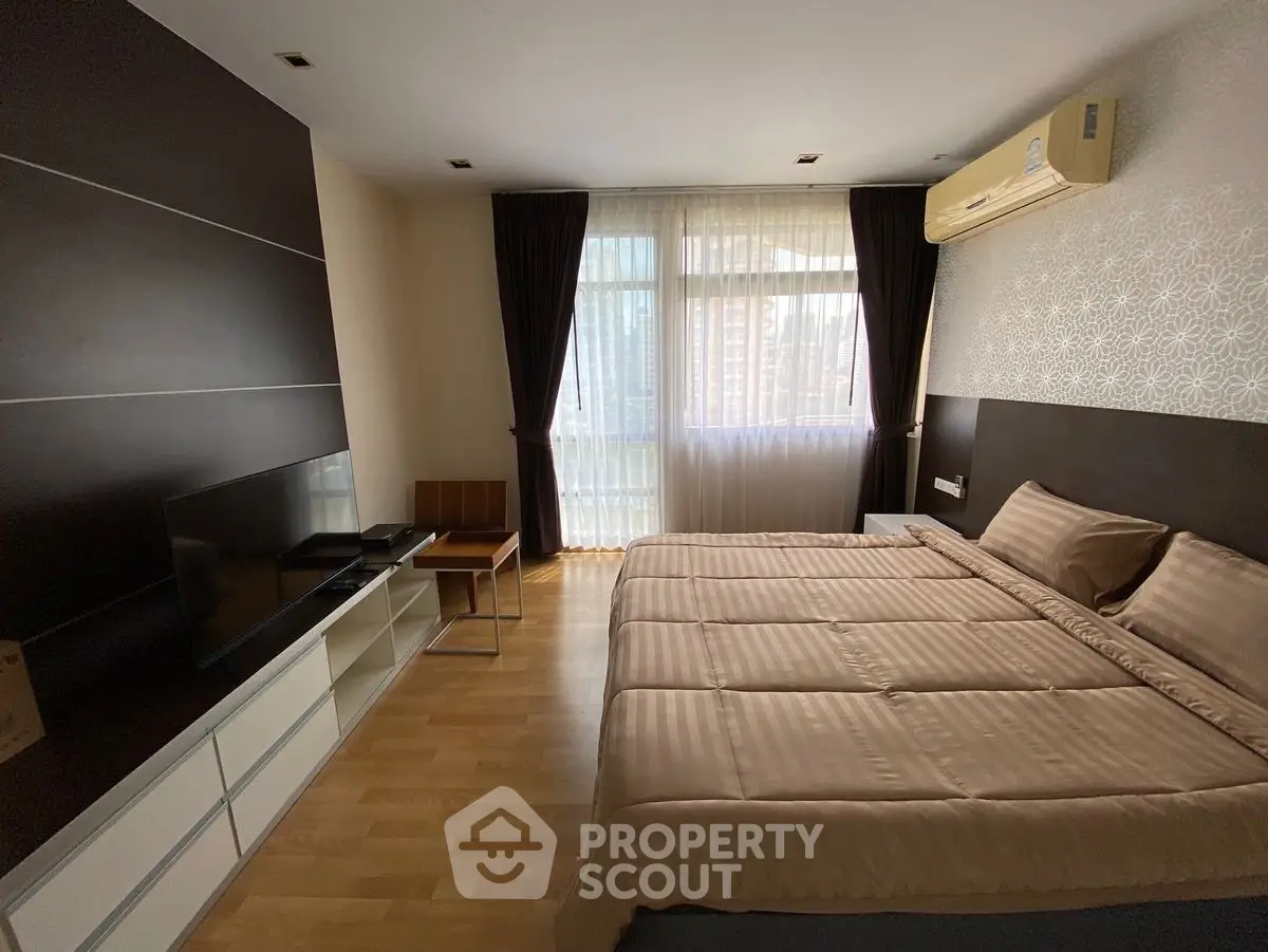 Spacious bedroom with modern decor and large window for natural light