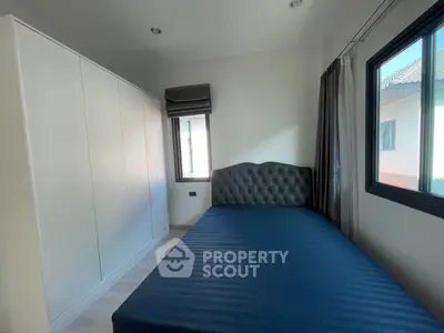 Cozy bedroom with modern design and ample natural light, featuring a stylish bed and spacious wardrobe.