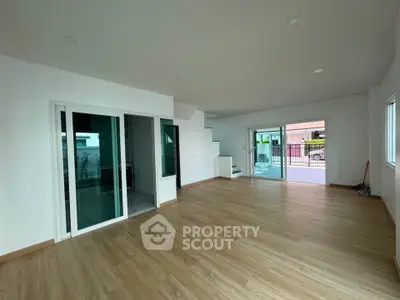 Spacious modern living room with wooden flooring and large glass doors leading to a balcony.