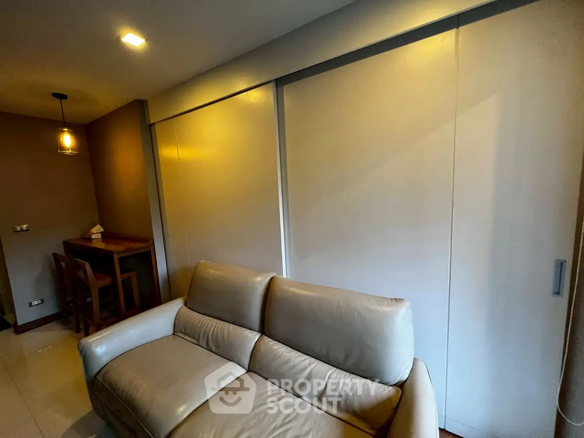 Modern living room with sleek leather sofa and stylish dining area, perfect for cozy urban living.