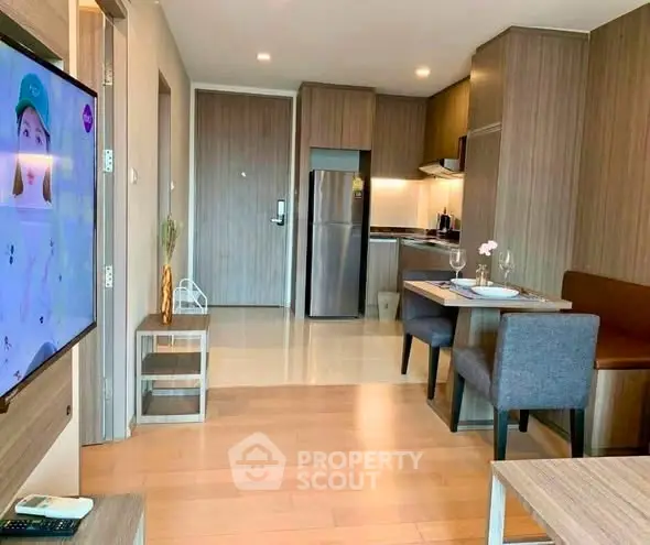Modern open-plan living room and kitchen with stylish wooden cabinetry and dining area.