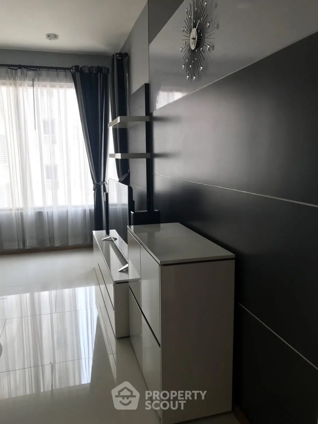 Modern living room with sleek black and white furniture and large window with curtains.