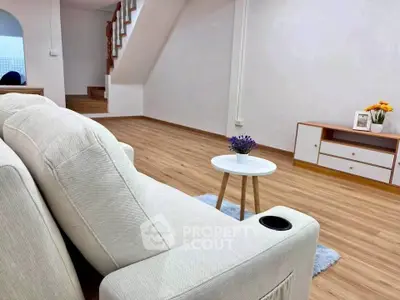 Spacious living room with modern decor and wooden flooring, featuring a cozy sofa and stylish furniture.