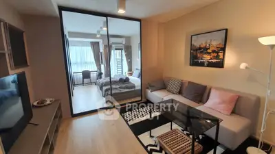 Modern living room with glass partition leading to a cozy bedroom, featuring stylish decor and ample natural light.