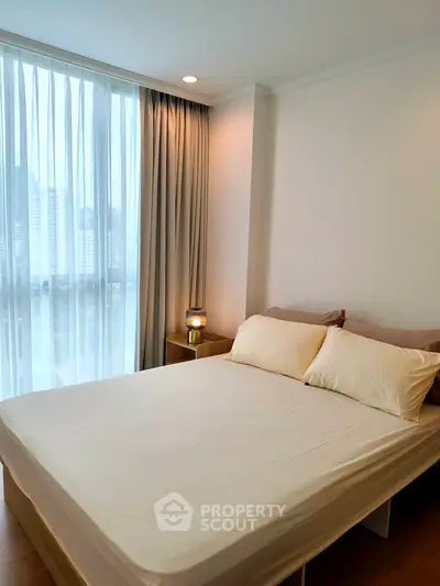 Modern bedroom with large window and elegant decor in a high-rise apartment.