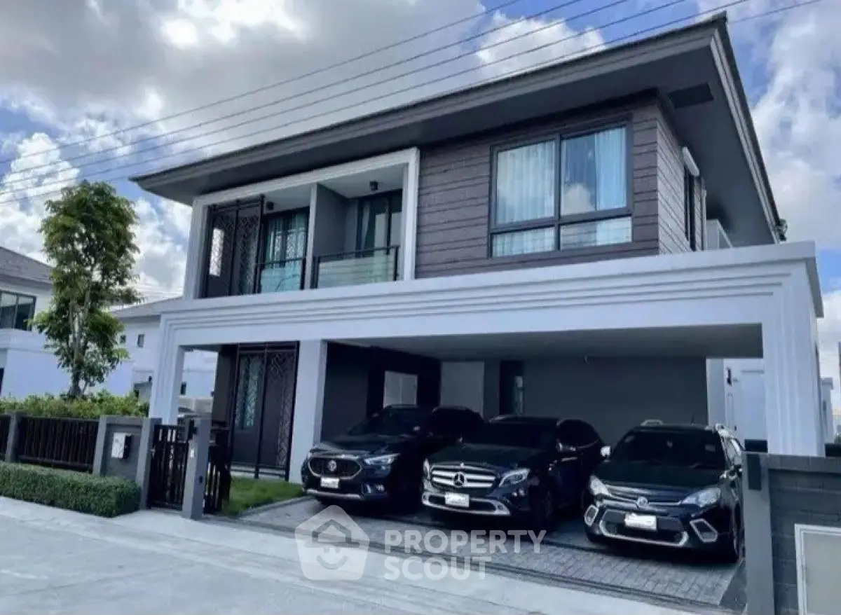 Modern two-story house with spacious driveway and luxury cars parked, showcasing contemporary architecture.