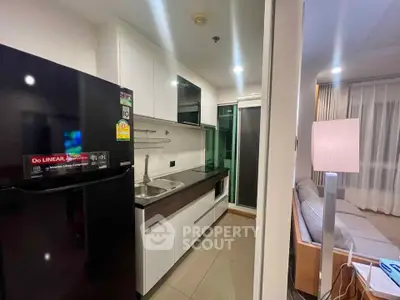 Modern kitchen with sleek cabinetry and adjacent cozy living area in a stylish apartment.