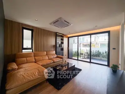 Modern living room with leather sofa and large sliding glass doors to patio