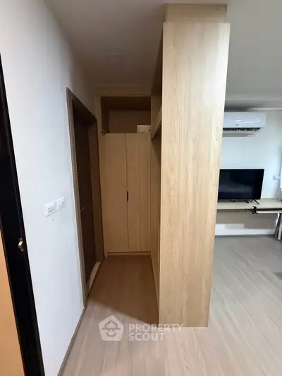 Modern apartment interior with wooden flooring and built-in storage, featuring a sleek TV setup.