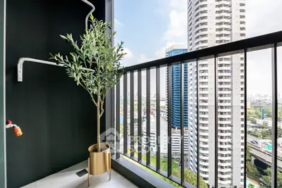 Modern balcony with stunning city view and potted plant, perfect for urban living.