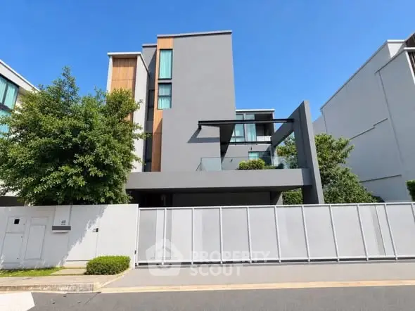 Modern minimalist house exterior with sleek design and lush greenery in a serene neighborhood.