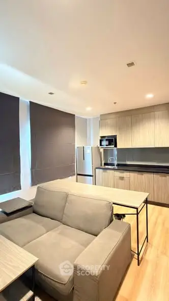 Modern living room with open kitchen, featuring sleek cabinetry and comfortable seating.
