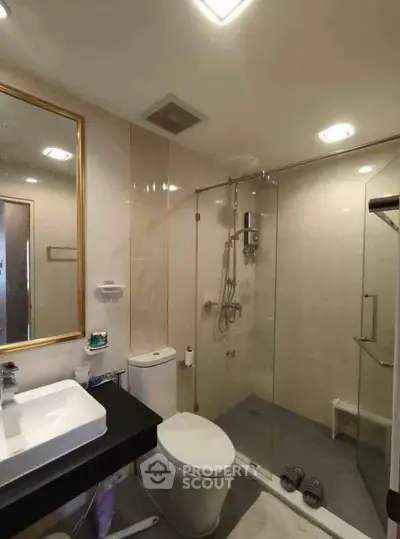 Modern bathroom with glass shower enclosure and sleek fixtures in a contemporary apartment.