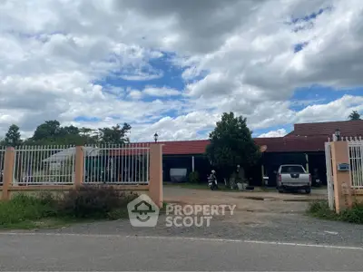 Charming countryside property with spacious driveway and lush greenery under a vibrant sky.