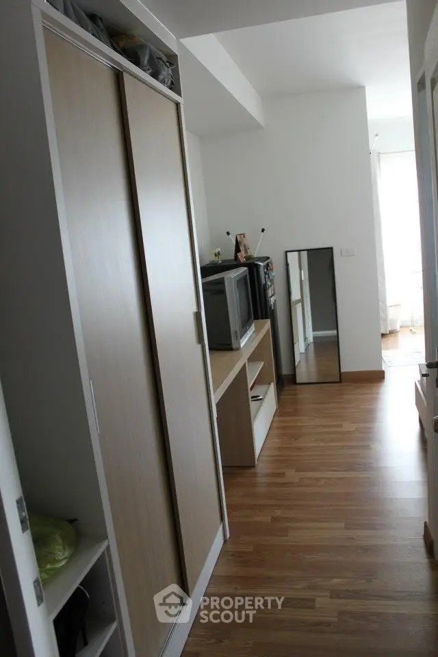 Spacious bedroom with wooden flooring and modern wardrobe in a bright apartment.