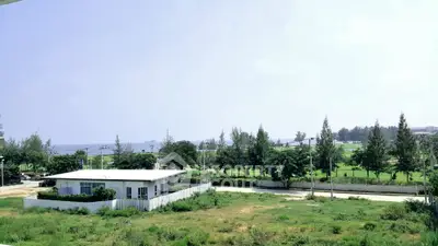 Scenic view of a modern house with lush greenery and distant ocean backdrop.
