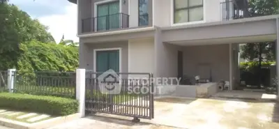 Modern two-story house with gated driveway and lush greenery, perfect for family living.