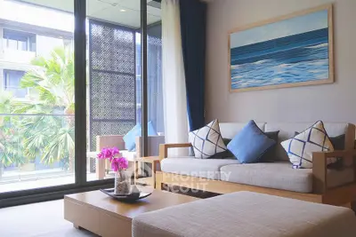 Modern living room with large windows and stylish decor overlooking lush greenery.