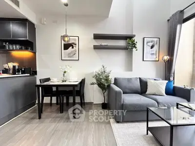 Modern living room with open kitchen, stylish decor, and natural light.