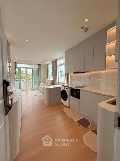 Modern open-plan kitchen and living room with sleek cabinetry and natural light.