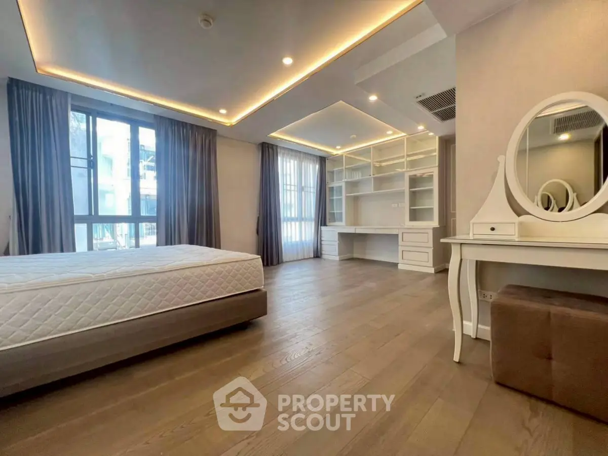 Spacious bedroom with elegant lighting and built-in study area, perfect for modern living.
