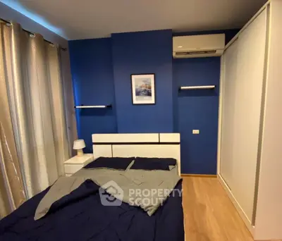 Modern bedroom with blue accent wall, sleek furniture, and cozy ambiance.