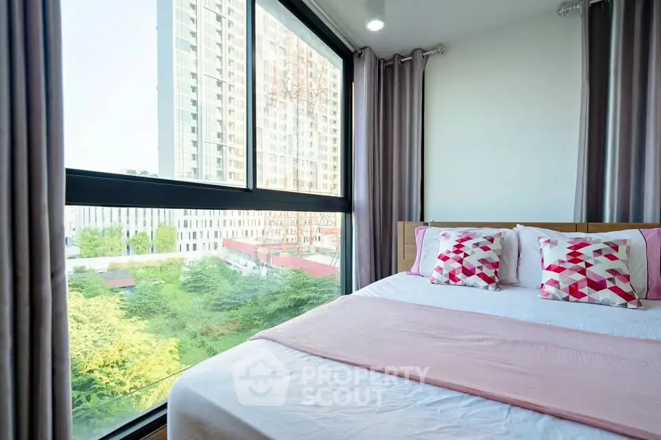 Bright bedroom with large window offering stunning city view in modern apartment.