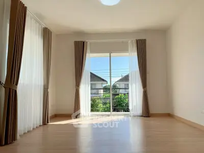 Spacious sunlit room with large windows and elegant curtains, perfect for a cozy living space.