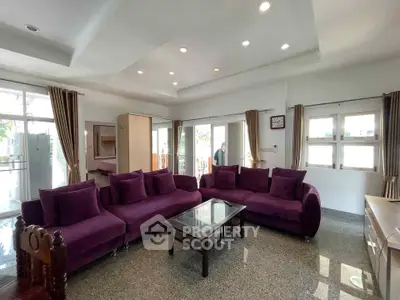 Spacious living room with purple sofas and large windows offering natural light.