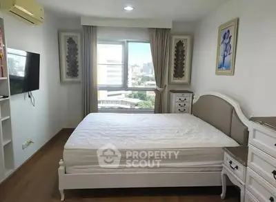 Spacious bedroom with elegant furniture and large window offering city views, perfect for relaxation.